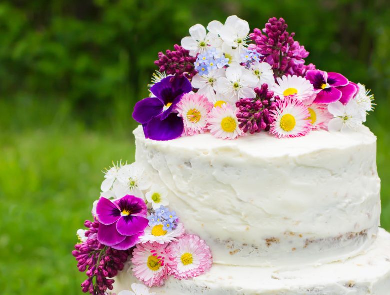 Semi-naked wedding cake with large colourful flowers